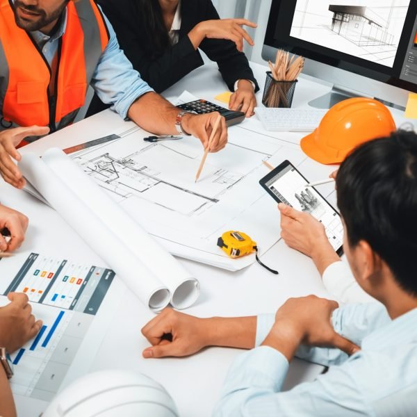 Diverse group of civil engineer and client working together on architectural project, reviewing construction plan and building blueprint at meeting table. Prudent