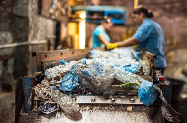 Plastic waste recycling factory Plastic garbage on a conveyor belt at waste recycling factory. Workers on the background